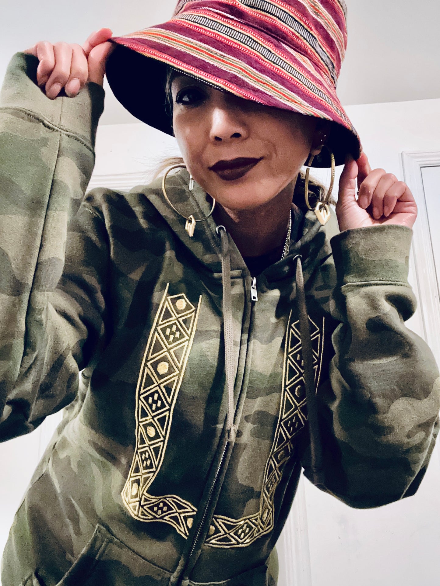 Person wearing a camouflage printed barong hoodie with geometric patterns and a colorful bucket hat