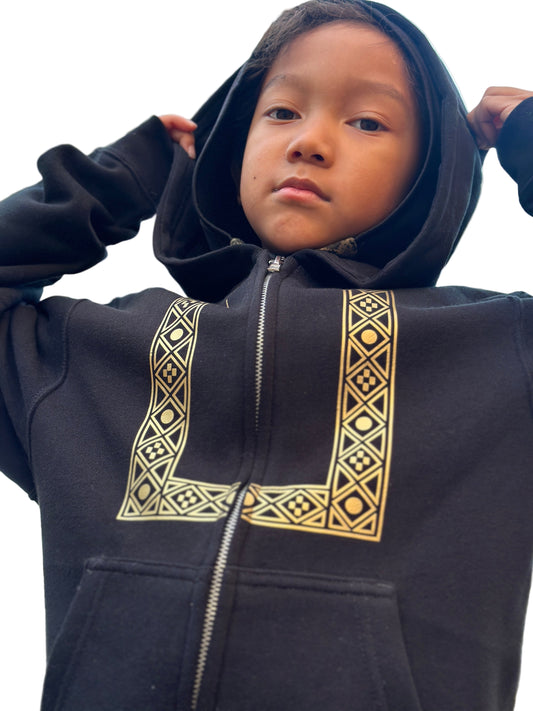 Child wearing a black zip up hoodie with gold geometric barong pattern